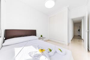 a bedroom with a white bed with two flowers on it at Aparthotel Laguna Rosa in Los Montesinos +111 photos