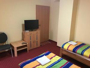 a room with two beds and a flat screen tv at Pension Rialto in Staufenberg