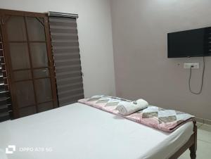 a bed in a room with a tv on the wall at JOSEPH'S HOMESTAY in Fort Kochi