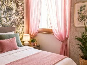 a bedroom with a bed and a window with pink curtains at FalcoBianco GuestHouse in Montefalco