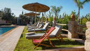 a row of lounge chairs with umbrellas next to a pool at Dar Eddihi Essaouira in Essaouira