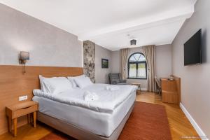 a bedroom with a large white bed and a television at Dokia Boutique in Gura Humorului