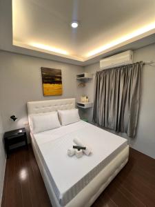 a bedroom with a large white bed with two towels at Stayhere Boracay Hostel in Boracay