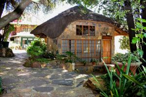a small house with a thatched roof at Gender Links Cottages in Johannesburg