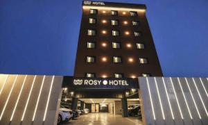 a hotel building with cars parked in a parking lot at Cheonan Asan Rosy Hotel in Asan