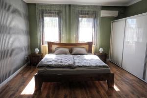 a bedroom with a bed with green walls and windows at Sziget Apartman in Pócsmegyer
