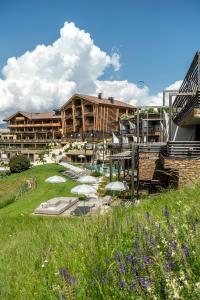 a resort with umbrellas in a field and a building at Hotel Valentinerhof in Siusi