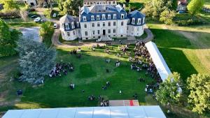 an aerial view of a large white house with a group of people on the grass at Gîte de la Tour in La Celle-sous-Gouzon