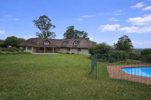 a house with a thatched roof and a pool at Pearse Farm Stay in Howick