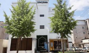 two trees in front of a white building at Pohang Villa Dahlia in Pohang