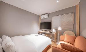 a bedroom with a bed and a desk with a television at Pohang Villa Dahlia in Pohang