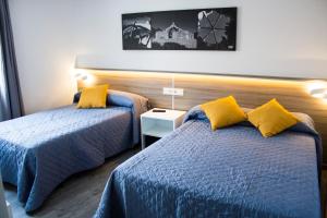a bedroom with two beds and a night stand at Pensión Mariola in Agres +103 photos