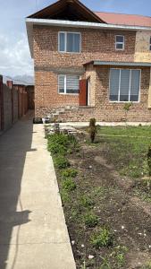 a brick house with a sidewalk in front of it at SunLake House in Balykchy +4 photos