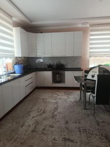 a kitchen with white cabinets and a table in it at SunLake House in Balykchy