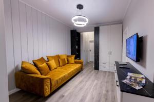 a living room with a yellow couch and a television at Apart Hotel Nordic Residence 16H in Suceava