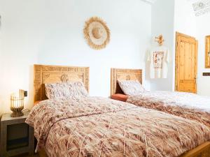 a bedroom with two beds and a tv in it at Sunset Surfhouse Morocco in Tamraght Ouzdar