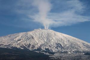 a snow covered mountain with smoke coming out of it at a casa di Norma in Bronte