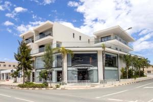 a white building with palm trees in front of it at Lake View Suites in Paralimni