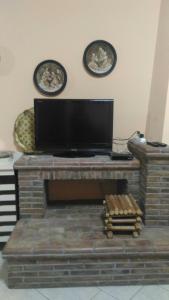 a flat screen tv sitting on top of a brick fireplace at a casa di Norma in Bronte