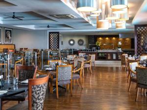 a restaurant with tables and chairs and a bar at ANEW Hotel Capital Pretoria in Pretoria