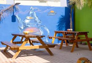two picnic tables in front of a wall with at Sunset Surfhouse Morocco in Tamraght Ouzdar