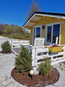 a yellow house with a white fence and two chairs at Pakri lighthouse camping in Paldiski