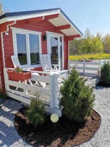 a red tiny house with two chairs and a fence at Pakri lighthouse camping in Paldiski