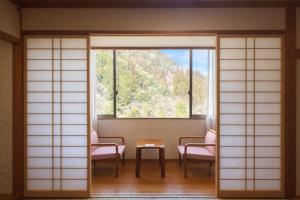 a room with a table and chairs and a window at ホテル秘境の湯 in Miyoshi