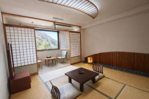 a room with a table and chairs and a window at ホテル秘境の湯 in Miyoshi