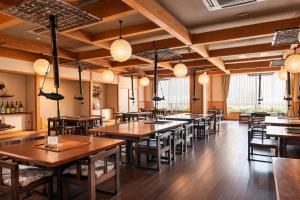 a restaurant with wooden tables and chairs and lights at ホテル秘境の湯 in Miyoshi