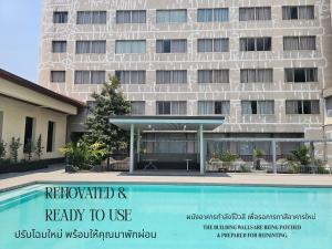 a hotel with a sign next to a swimming pool at Songphanburi Hotel in Suphan Buri