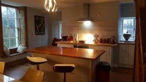 a kitchen with a wooden counter and stools at Grigshot Apartment in Stroud