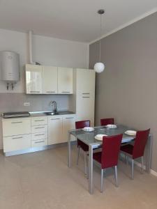 a kitchen with a table and red chairs in a room at Duca d Aosta apartment 2 in Monfalcone