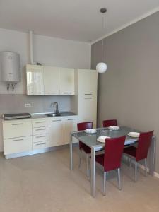 a kitchen with a table and red chairs in a room at Duca d Aosta apartment 2 in Monfalcone