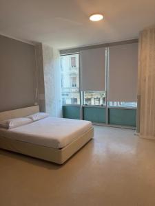 a bedroom with a large bed and large windows at Duca d Aosta apartment 2 in Monfalcone