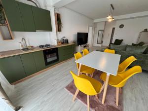 a kitchen and living room with a table and yellow chairs at DaVinci Apartments VRT in Cristian