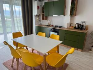 a kitchen with a white table and yellow chairs at DaVinci Apartments VRT in Cristian +7 photos