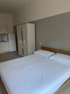 a large white bed in a room with a kitchen at Duca d Aosta apartment 4 in Monfalcone