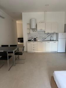 a kitchen with white cabinets and a table and chairs at Duca d Aosta apartment 4 in Monfalcone