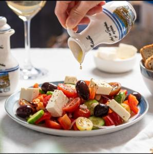 a person pouring cheese on a plate of vegetables at Sunshine in Olympiada