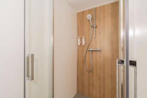 a shower in a bathroom with a wooden door at Buitenplaats Hotel met terras, studio in Ellemeet