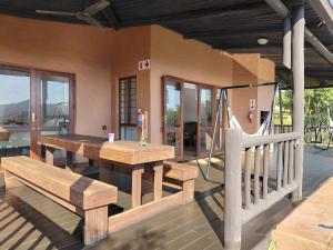 a porch with a wooden table and benches on a house at Sickle Bush Da Gama Lake in White River