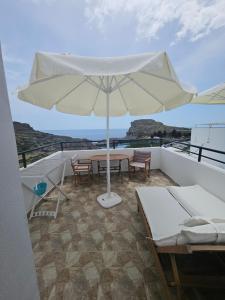 a white umbrella on a balcony with a table and chairs at St Paul's Studios Chrysanthi in Lindos