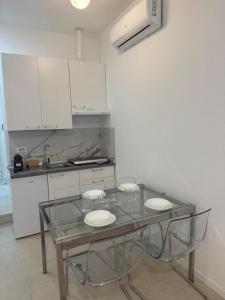 a glass table in a kitchen with white cabinets at Duca d Aosta apartment 3 in Monfalcone