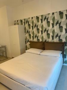 a bedroom with a white bed with a patterned wall at Duca d Aosta apartment 3 in Monfalcone