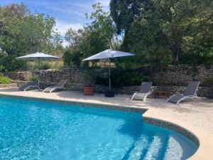 a swimming pool with two chairs and umbrellas at Le Verger in Gordes +112 photos