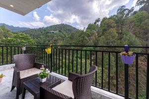 a balcony with two chairs and a table with a view at A Mountains Suffer Hotel Kasauli Near Kasauli Hills Resort by Splendid Retreat Hotels - Family Groups - Balcony - Parking - Mountain View - River View - Forest Treks - Vacation - Memories in Kasauli