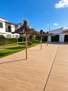 a row of straw umbrellas on a patio at Cala Porter Soleil & Mer Collection in Cala en Porter
