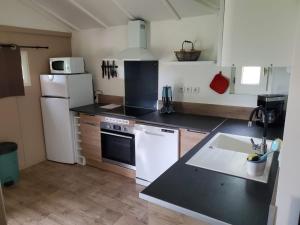 a kitchen with white appliances and a black counter top at Les chalets du Causse Confort Climatisé in Gelle