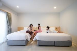 three girls sitting on beds in a hotel room at Manditel North Pattaya in North Pattaya